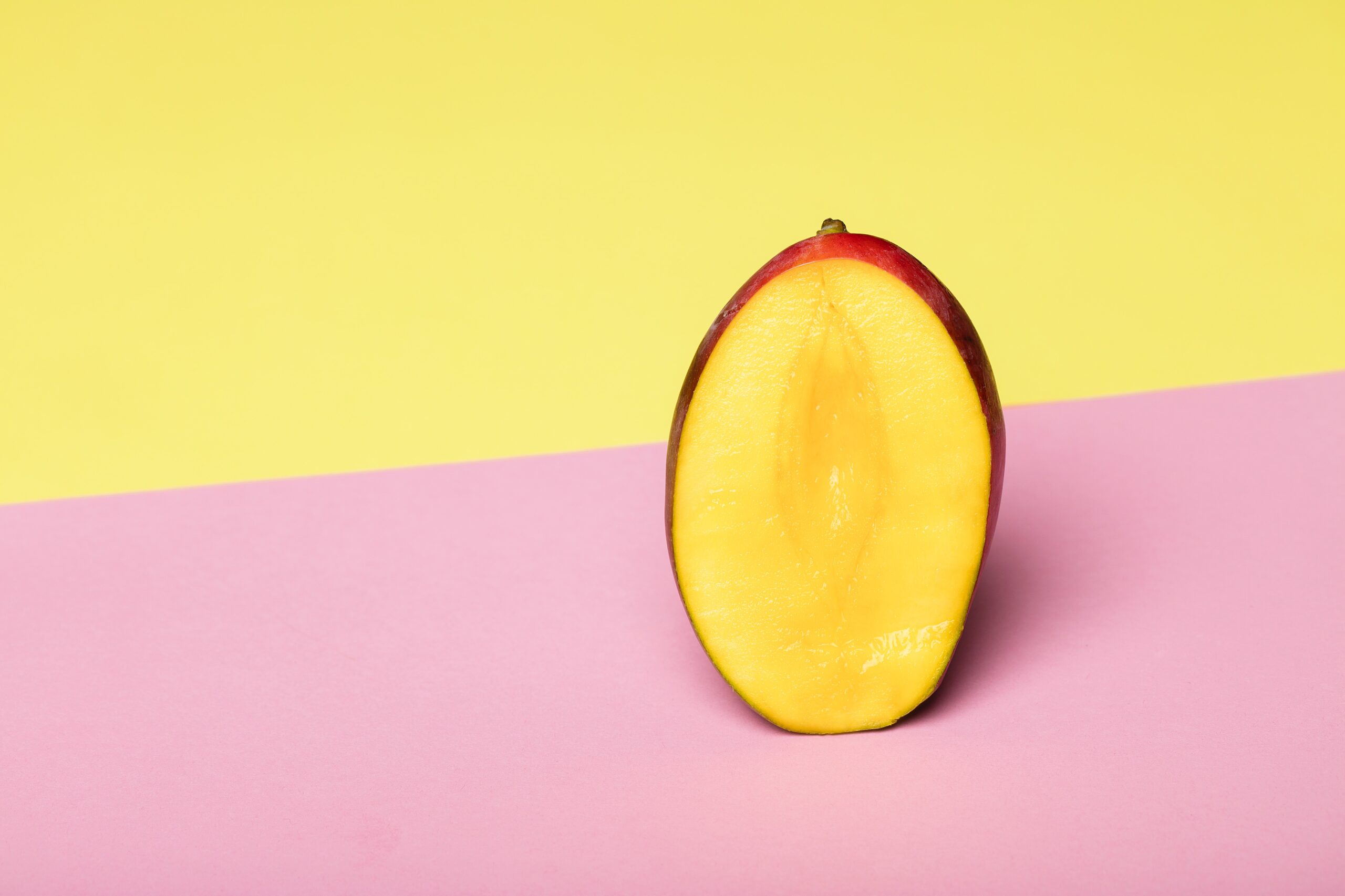 Sliced open mango on a pink and yellow background